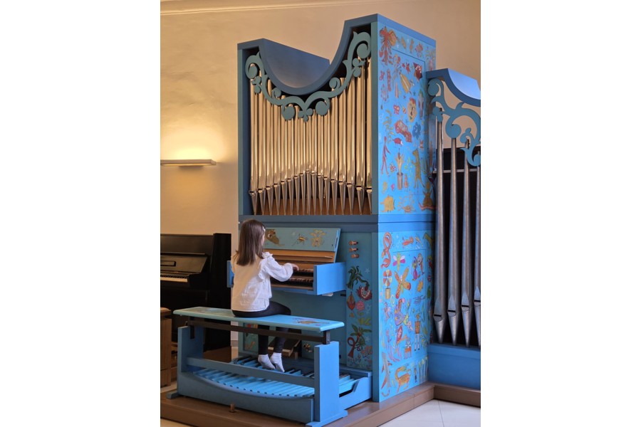 Kind das an einer Orgel sitzt